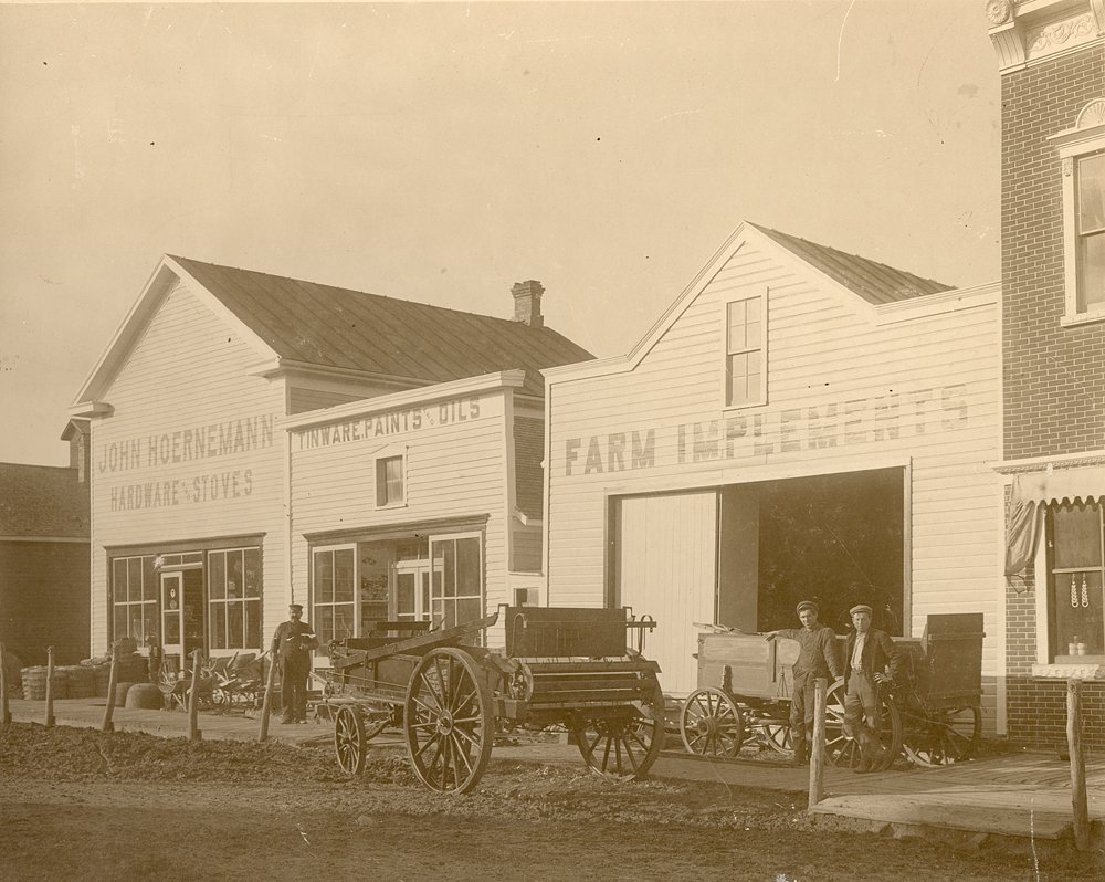 John Hoerneman Sr, Henry Hoernemann, F. Kohls standing in front of stores on main street